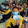 Alunos seguram folhetos com informações de saúde sobre Covid-19 em sala de aula na província de Qinghai, China.