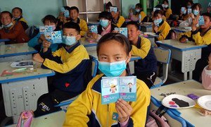 中国青海省的一间教室里，学生们手持有关新冠疫情健康教育手册。