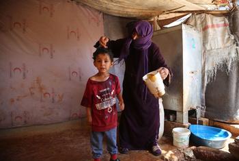 Una mujer moja a un niño en Siria para ayudarle a refrescarse un poco.