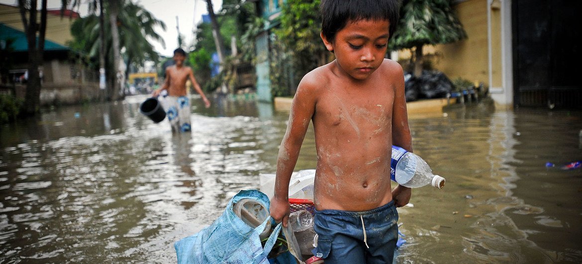 طفل صغير يمشي في شارع غمرته الفيضانات في أعقاب إعصار، في أحد شوارع العاصمة الفليبينية مانيلا.