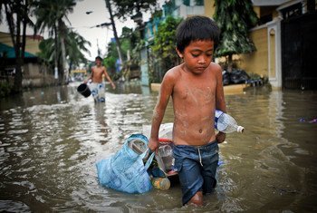 台风过后，一名男孩拖着自己的东西穿过马尼拉被洪水淹没的街道。（资料图片）
