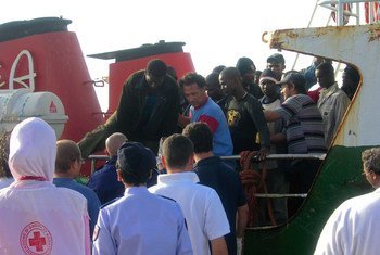 कुछ प्रवासीजन इटली के लैम्पीडूसा में एक जहाज़ से उतरते हुए.