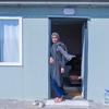 Emel stands by the door of her new home – a 32-square-metre container she moved into with her husband and four children after living in a tent for three months.