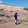 Une Palestinienne se tient debout dans un paysage désolé, jonché de débris et de deux pneus, regardant vers un flanc de colline endommagé à l'est de Naplouse.