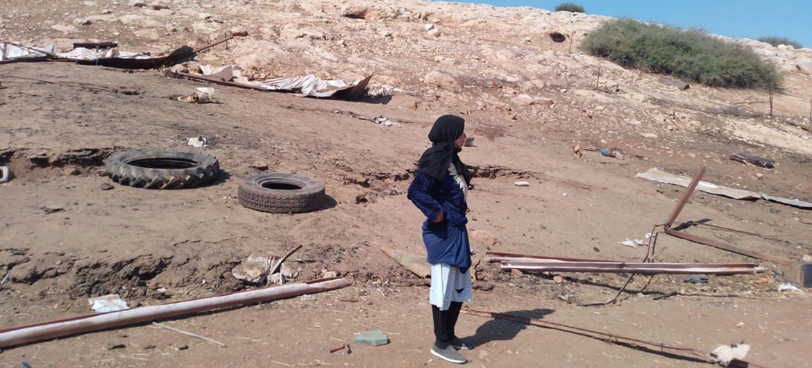 Une Palestinienne se tient debout dans un paysage désolé, jonché de débris et de deux pneus, regardant vers un flanc de colline endommagé à l'est de Naplouse.
