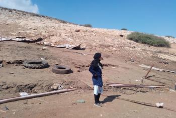 Une Palestinienne se tient debout dans un paysage désolé, jonché de débris et de deux pneus, regardant vers un flanc de colline endommagé à l'est de Naplouse.
