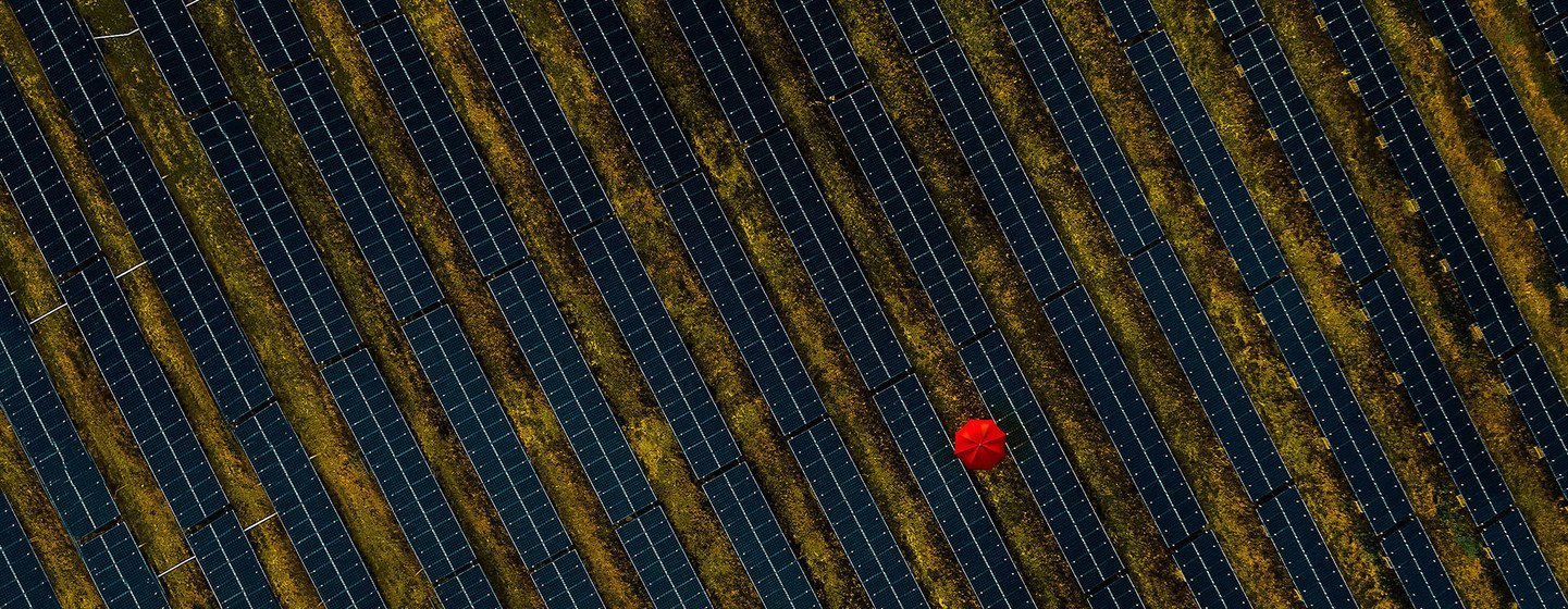 Une personne portant un soleil rouge se promène dans une ferme de panneaux solaires en France.