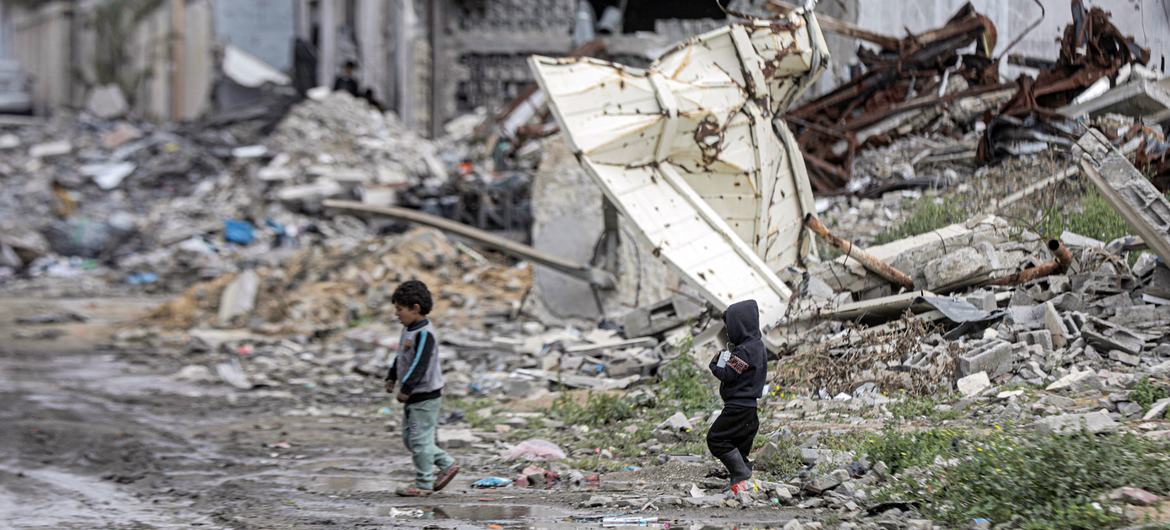 Two children walk through Gaza's destroyed landscape.