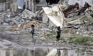 Two children walk through Gaza's destroyed landscape.