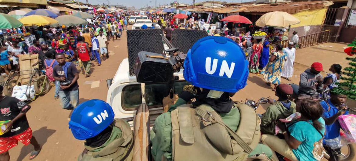 UN peacekeepers in blue helmets ride through a bustling market in the Central African Republic, supporting election efforts in coordination with UNDP RCA.