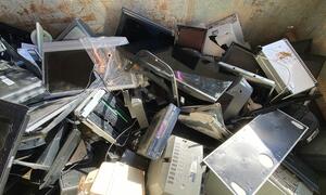 Una pila de dispositivos electrónicos desechados que incluyen computadoras, monitores y televisores, destacando el problema de los residuos electrónicos y la necesidad de una eliminación y reciclaje adecuados.