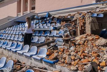Une étudiante ukrainienne de 17 ans nommée Sofiia se tient parmi les sièges détruits d'un stade de Kharkiv, en Ukraine. La tribune a été endommagée par des bombardements, avec des décombres et des chaises en plastique brisées éparpillées. Sofiia, qui rêve de devenir médecin, fait partie d'un programme de récupération de l'apprentissage soutenu par l'UNICEF pour aider les élèves à rattraper l'éducation perturbée par la guerre.