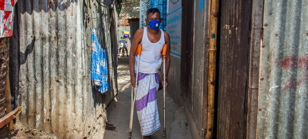 在孟加拉国的一个城市街区，一名残疾人拄着拐杖走路。