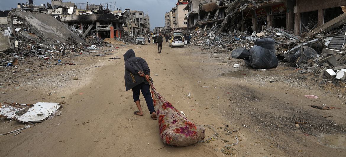 在加沙地带南部的汗尤尼斯，一个人正拖着自己的财物穿行在街道上。
