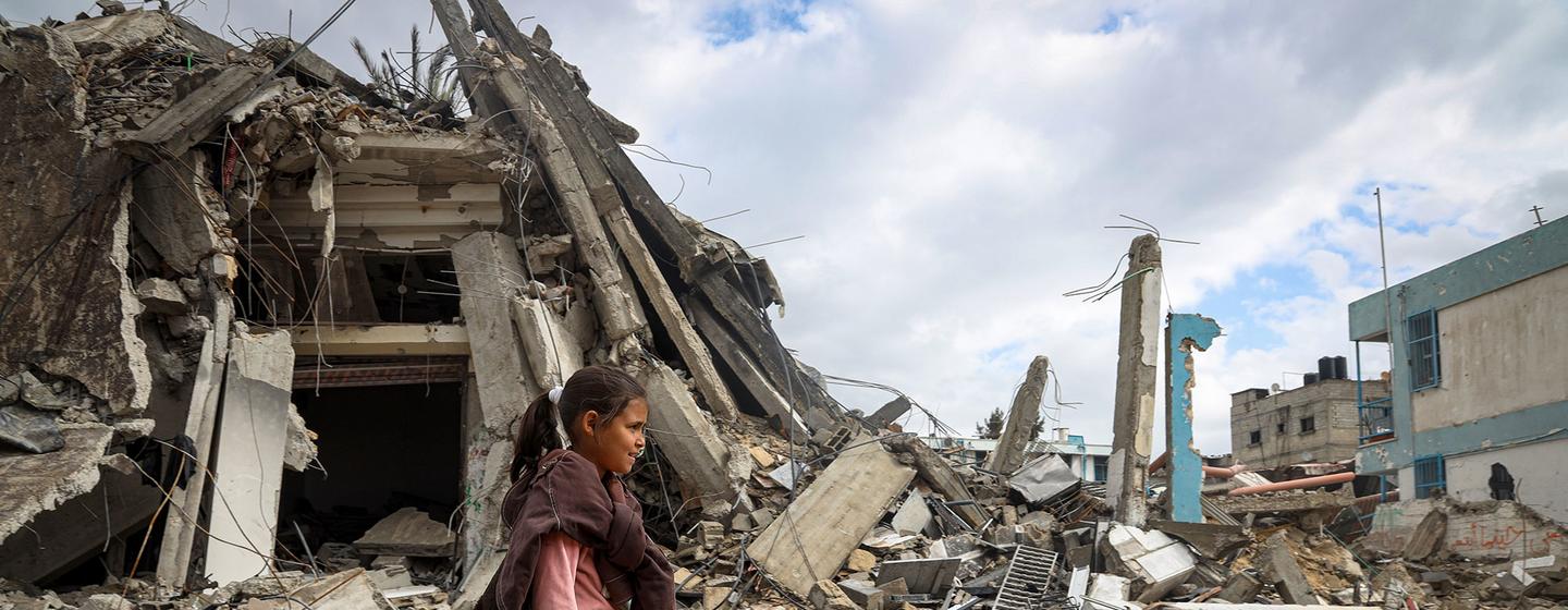 在加沙地带南部的汗尤尼斯，一名年轻女孩走过被摧毁的街道。