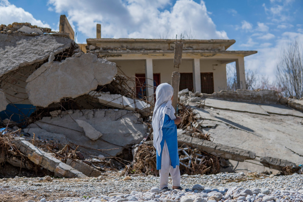 An eight-year-old girl stands near a school destroyed by floods in Quetta, Pakistan.