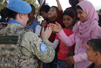 Un miembro del personal de mantenimiento de la paz saluda a los alumnos de la Escuela Faouar en Siria, que fue una de las cuatro escuelas rehabilitadas por la Fuerza de Retirada de las Naciones Unidas.