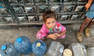 A child waits to fill water containers in Gaza.