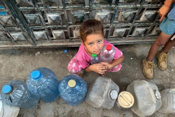 ग़ाज़ा में एक बच्चा पानी की बोतलों को भरने की प्रतीक्षा कर रहा है.