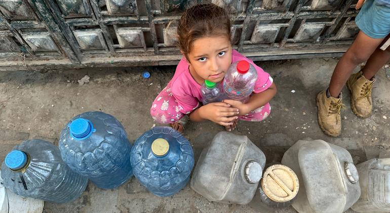 Uma criança espera para encher recipientes de água em Gaza.