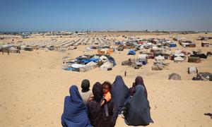 Women look across a temporary camp near the Philadelphi Corridor in Rafah, Gaza.