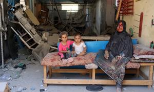 Una mujer y sus hijos se sientan dentro de su casa destruida, en Burij, en el centro de la Franja de Gaza.