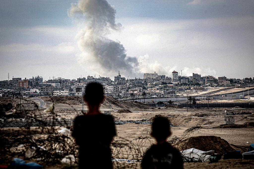 Dos niños observan columnas de humo tras un ataque aéreo sobre la ciudad de Gaza.