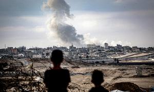 Dos niños observan columnas de humo tras un ataque aéreo sobre la ciudad de Gaza.