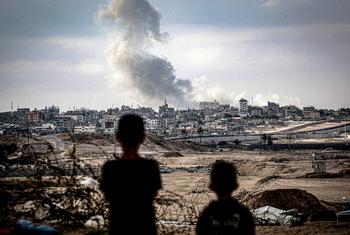 Two children watch plumes of smoke rise after an airstrike hit Gaza City. (file)