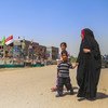 ماں اور بچے عراقی شہر بابل کے ’الشہدا سٹیڈیم‘ کے پاس سے گزر رہے ہیں۔ یہ یادگار اس جگہ تعمیر کی گئی ہے جہاں ایک خودکش حملہ ہوا تھا جس کی ذمہ داری داعش نے قبول کی تھی۔
