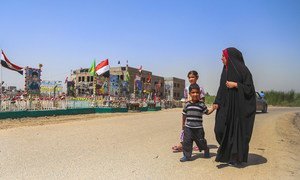 A family walks past a memorial set up at  the location of a suicide bombing, claimed by ISIL, at Al-Shuhadaa Staduim in Babil, Iraq.