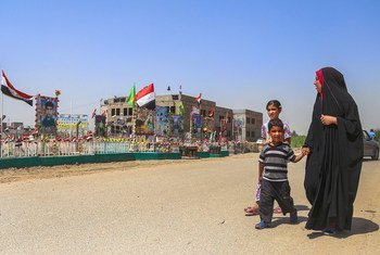 在伊拉克巴比勒，一个家庭走过恐怖袭击纪念碑。
