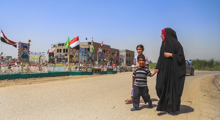 A family walks past a memorial set up at  the location of a suicide bombing, claimed by ISIL, at Al-Shuhadaa Staduim in Babil, Iraq.