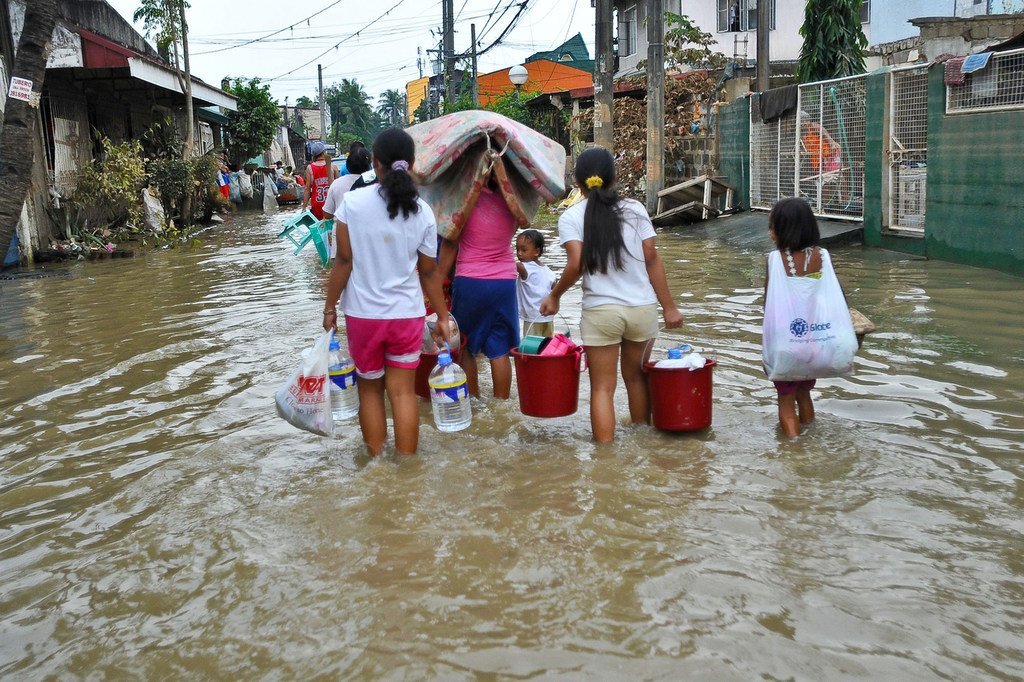 Residents of Manila walk through a flooded street during Typhoon Ketsana, carrying relief supplies and belongings.
