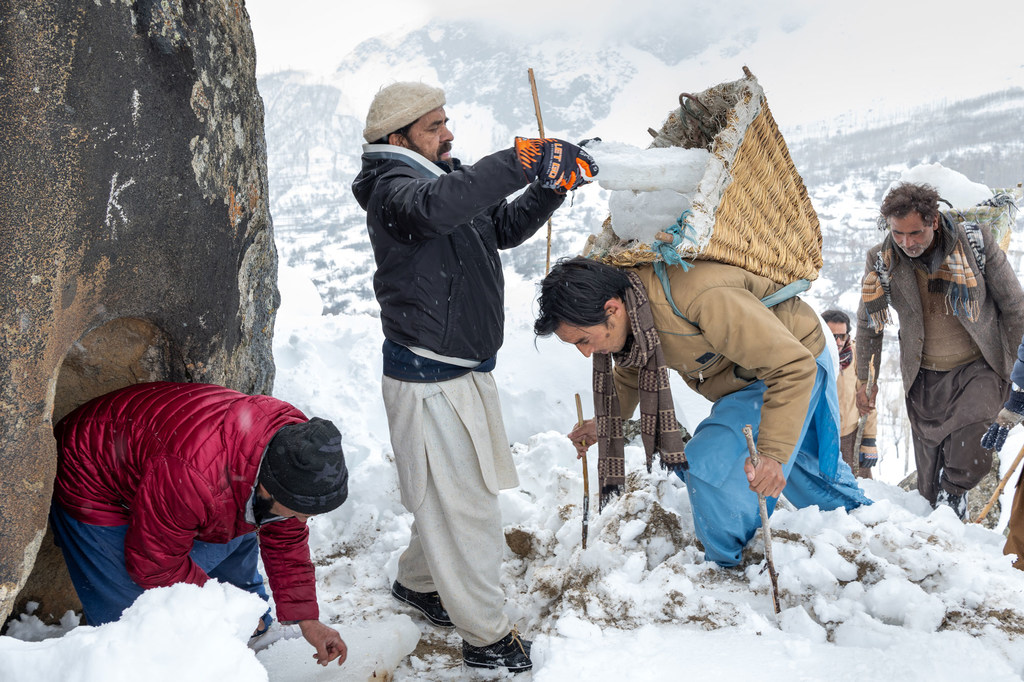 पाकिस्तान के पहाड़ी, बर्फीले इलाके में पुरुष एक हिमनदी प्रत्यारोपण परियोजना के तहत बर्फ और हिम के साथ काम कर रहे हैं।