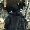 Mwanamke aliyevaa abaya nyeusi akitembea kwenye vifusi vya jengo lililoporomoka huko Khan Younis, Ukanda wa Gaza.