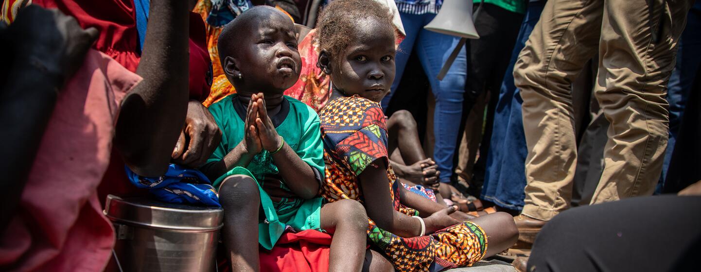 Des enfants déplacés par la violence dans l'État de Jonglei, au Soudan du Sud, sont assis devant une église épiscopale à la recherche d'une aide humanitaire, un enfant se tenant par la main en prière.