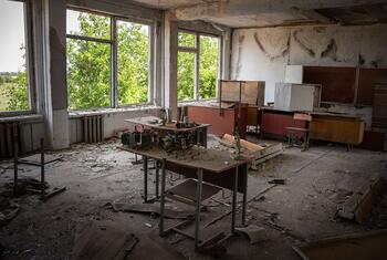 युद्धग्रस्त यूक्रेन में एक ध्वस्त स्कूल कक्षा, टूटी हुई फर्नीचर और क्षतिग्रस्त दीवारों के साथ, शिक्षा और दैनिक जीवन पर यौन हिंसा और संघर्ष के प्रभाव का प्रतीक।