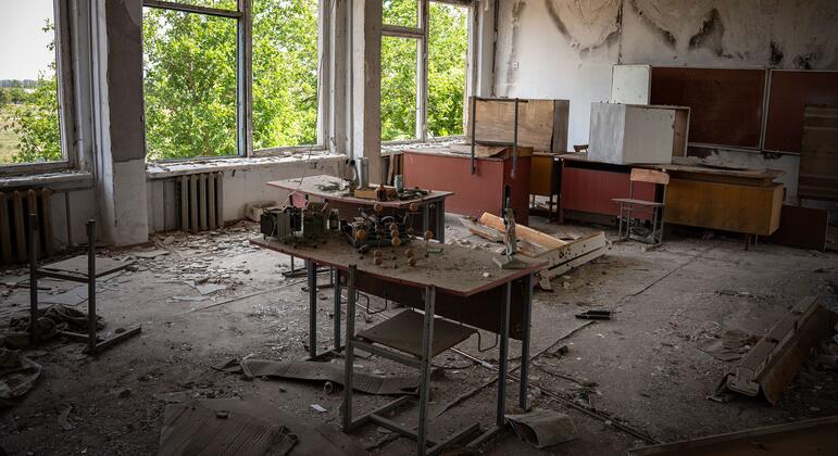 Разрушенный класс в разрушенной школе в раздираемой войной Украине, с разбитой мебелью и поврежденными стенами, символизирующие влияние сексуального насилия и конфликта на образование и повседневную жизнь.