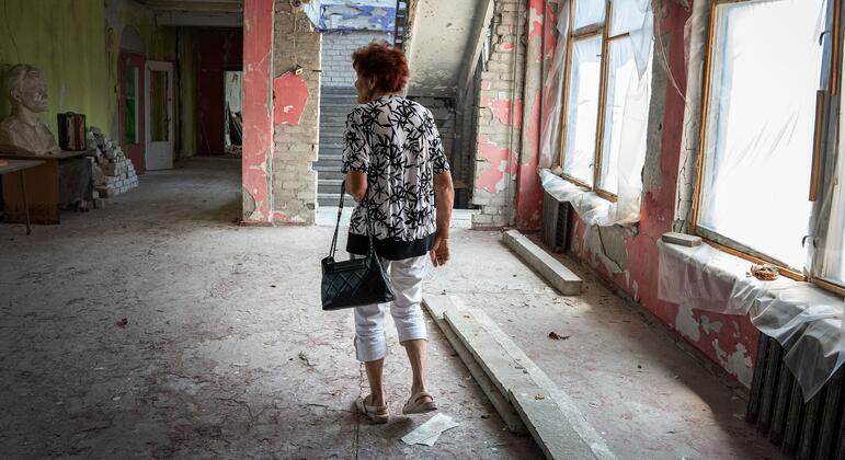 Женщина гуляет по наполовину разрушенным, наполовину отремонтированным коридорам школы в раздираемой войной Украине, размышляя о счастливых временах в качестве учительницы.