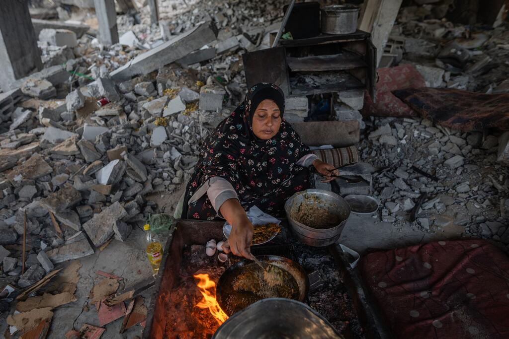 A woman cooks dinner in the ruins of her home in Gaza.