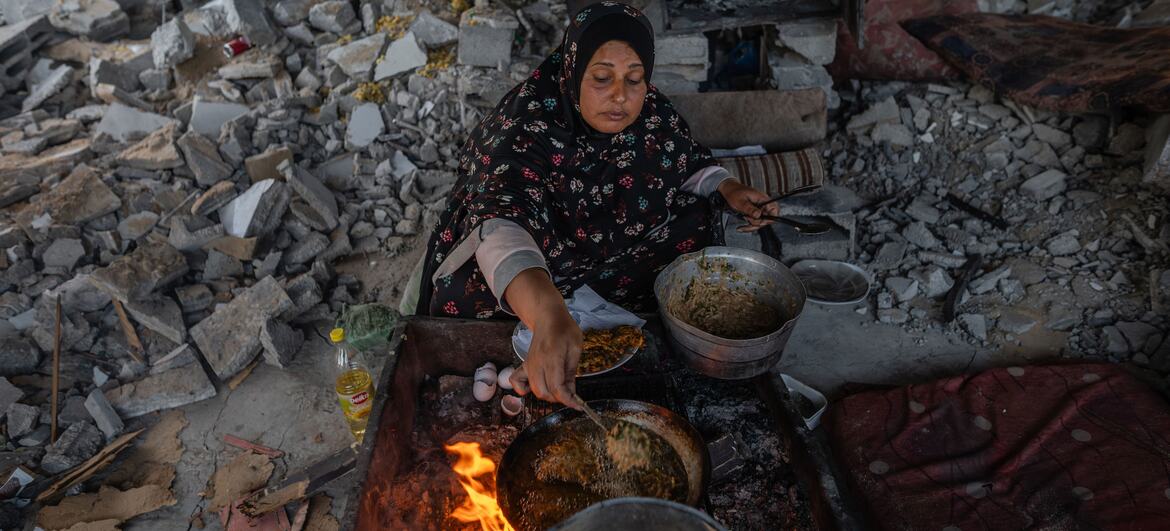 A woman prepares iftar in a tent amidst rubble in Gaza City, after her home was destroyed during the war. Her family relies on WFP assistance for survival.
