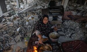 A woman prepares iftar in a tent amidst rubble in Gaza City, after her home was destroyed during the war. Her family relies on WFP assistance for survival.