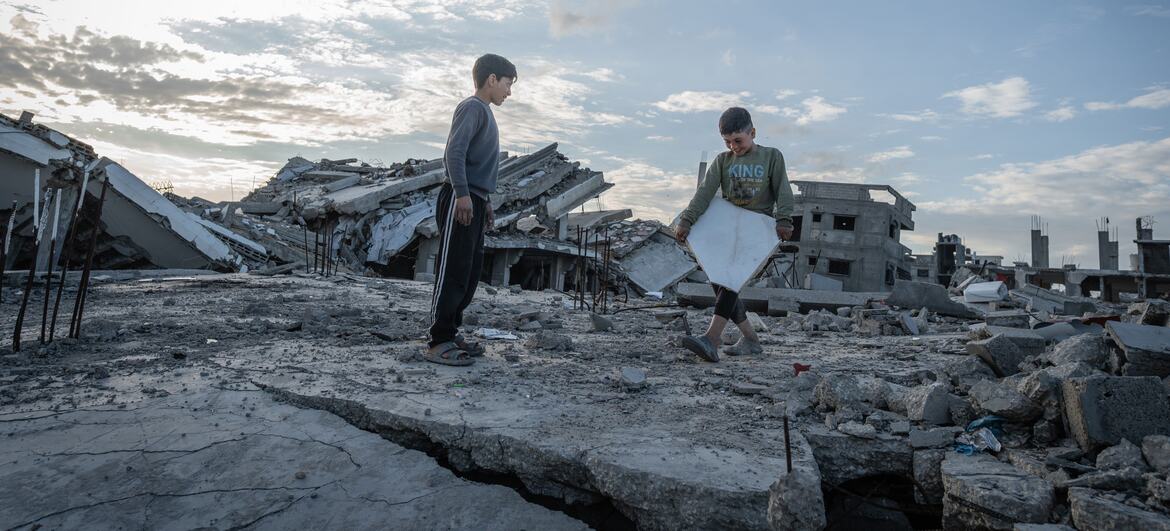 Two Palestinian children, Yazan (10) and Ali Muhammad (7), play on the debris of their destroyed home in Al-Zarqaa, Gaza City, after returning from displacement due to war, now living in a tent and relying on WFP assistance.