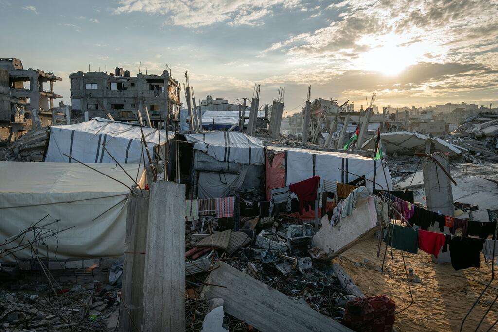 Une famille d'Al-Zarqaa, dans la ville de Gaza, vit dans une tente de fortune sur les décombres de leur maison détruite, dépendant du PAM et de l'aide humanitaire pour survivre.