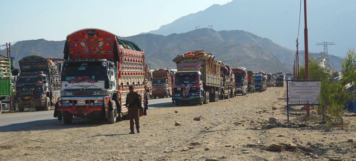 Une ligne de camions colorés transportant des rapatriés afghans et leurs effets personnels arrive au poste frontalier de Torkham entre l'Afghanistan et le Pakistan, avec les services d'aide de l'UNICEF prêts au camp d'Omari.