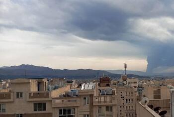 在剧烈的暴风雨云下的德黑兰屋顶的全景景观,远处有雨,地平线上可见的山脉.