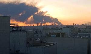 Una vista panorámica del horizonte de Teherán al atardecer, con una gran columna de humo oscuro que se eleva en la distancia detrás de los edificios de hormigón de la ciudad.