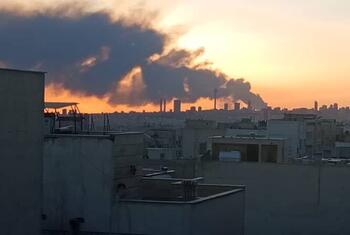 太阳落下的德黑兰天际线的全景景观, 距离城市的混凝土建筑背后起的大片黑烟雾.