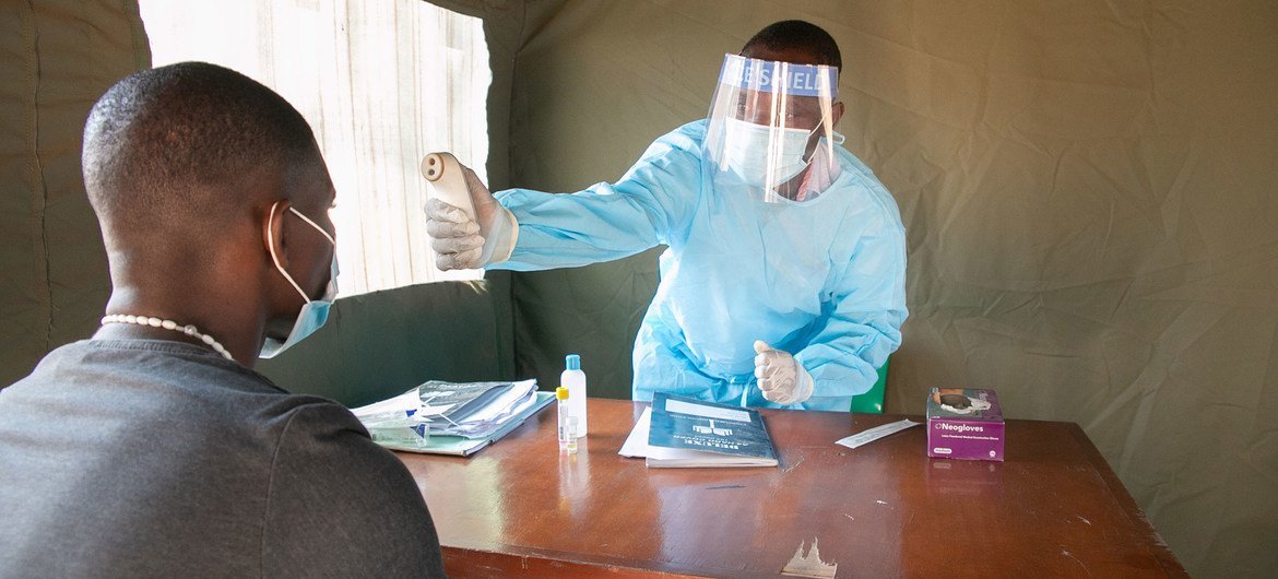 A health worker checks a patient’s temperature at one of the screening sites set up in Mangochi with UN support.  